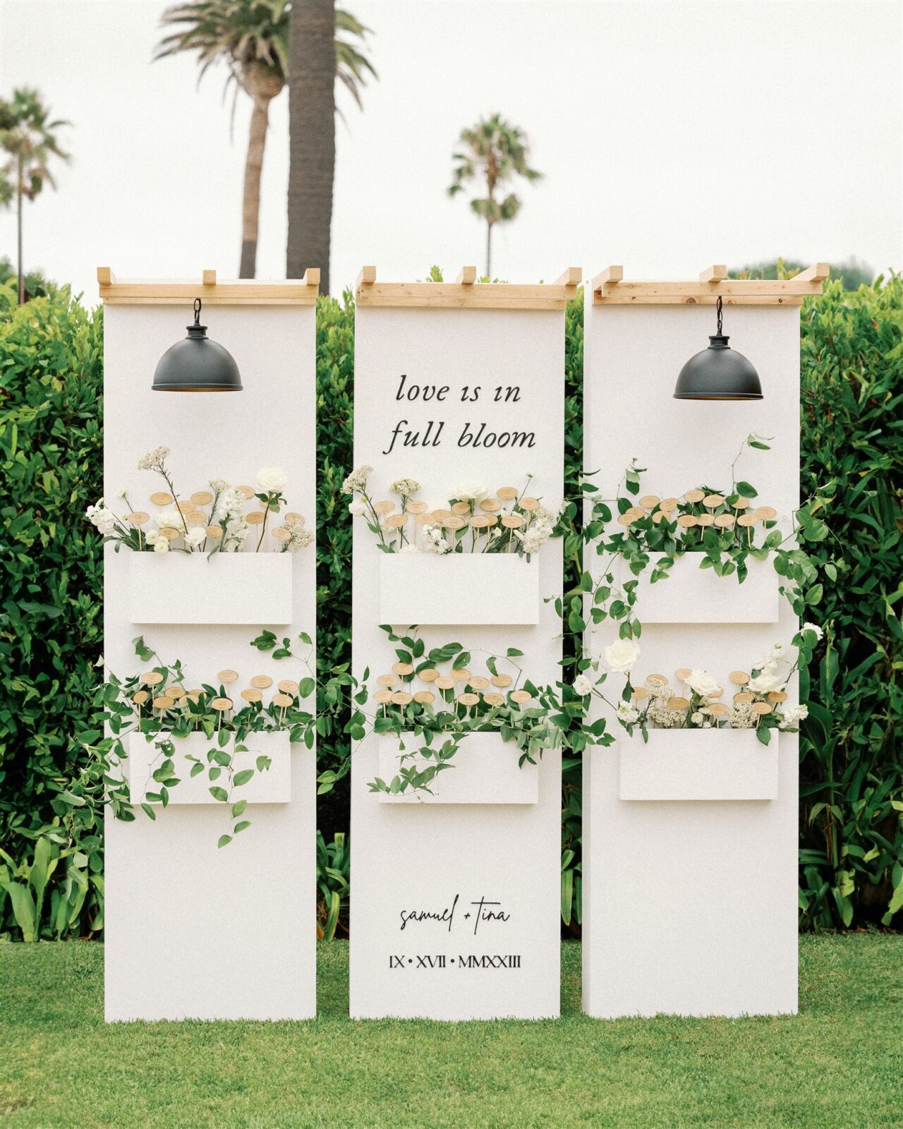 Modern garden box wedding seating chart display with greenery and lamps