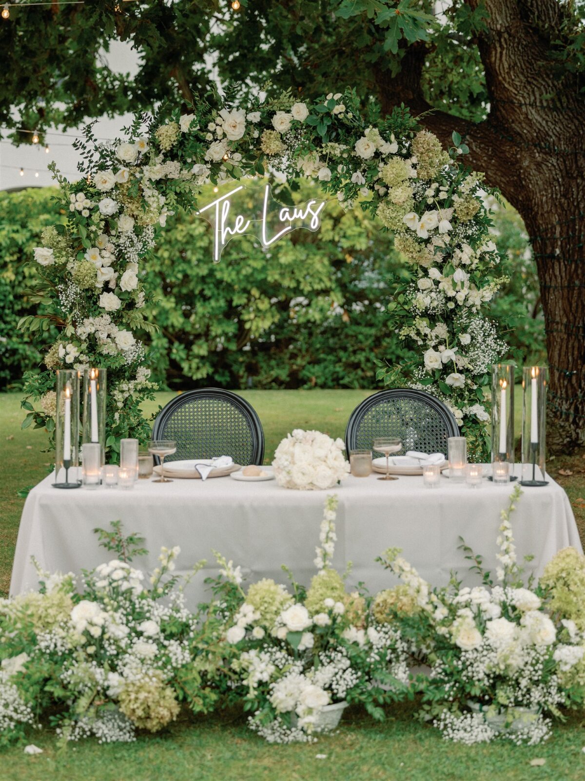 Sweetheart table with white and green floral and a neon sign at the La Jolla Women's Club