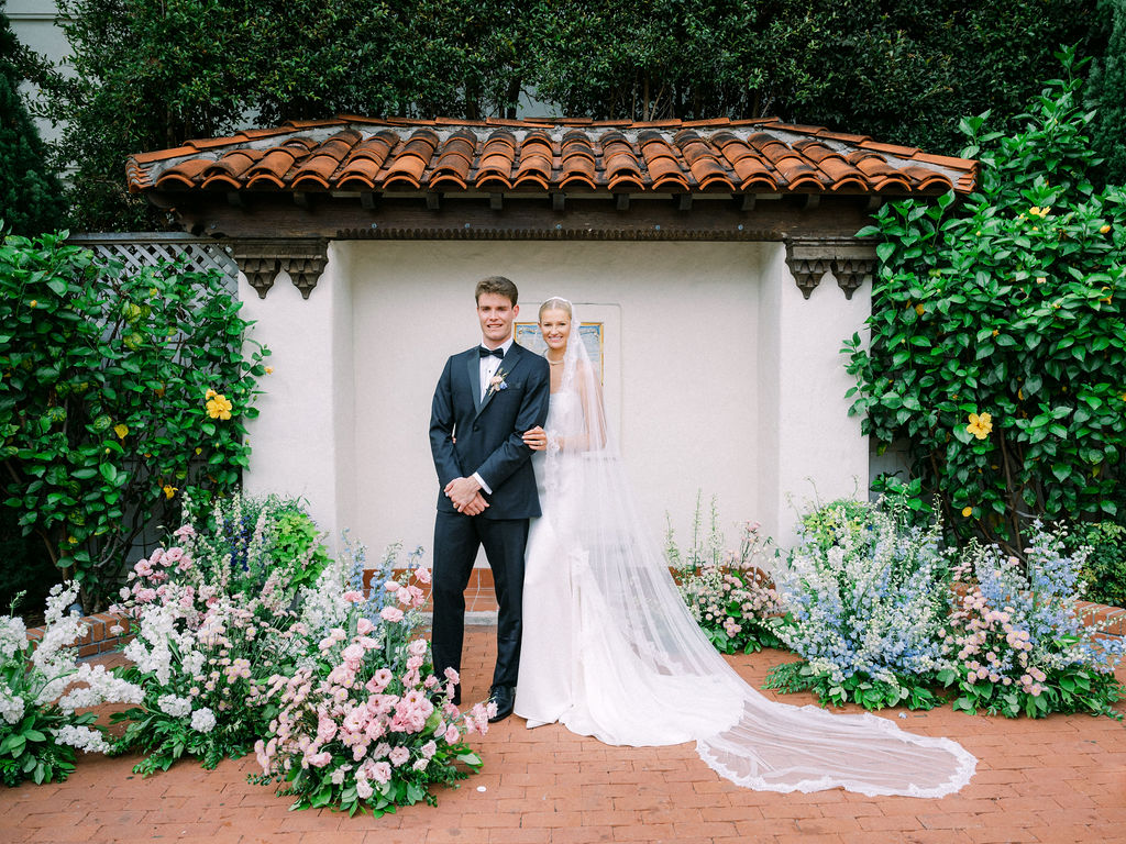 Bride and groom posing at the front of the ceremony in the Rose Garden at the Darlington House