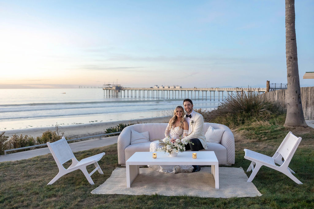 bride and groom sitting on a lounge at their wedding at Scripps Seaside Forum