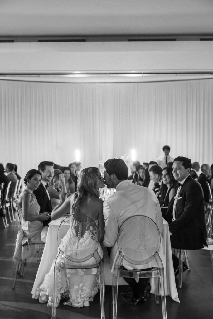 Bride and groom kissing during dinner at wedding reception at Scripps Seaside Forum